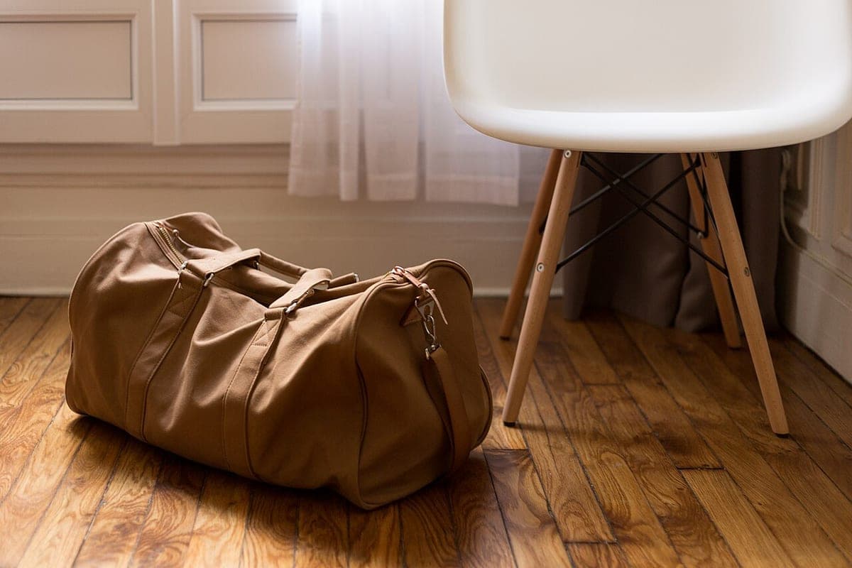 A soft duffel bag on the floor beside a chair